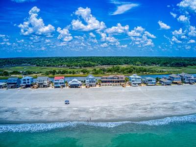 Airal photo of a beach on Pawley`s Island, several houses strung across the beach with large swath of natural land behind them.